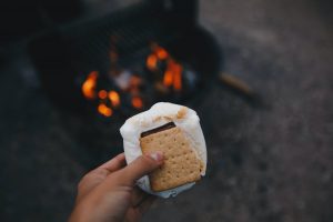 Holding up s’mores against a camp fire