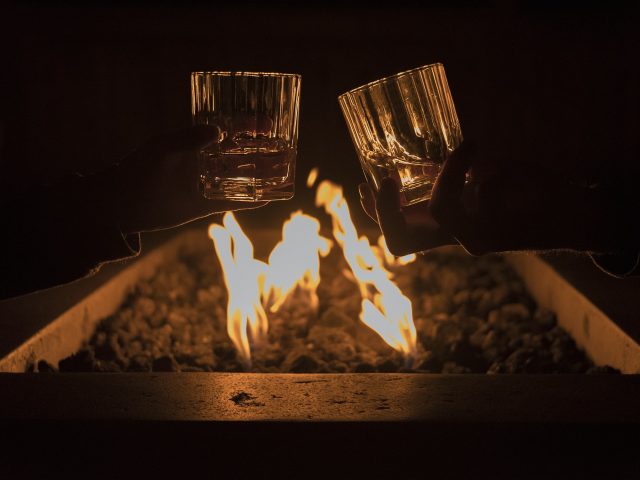 Toasting drinks by fire pit.